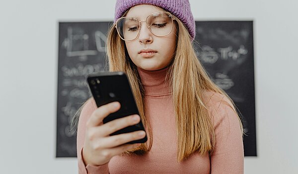Junge Frau schaut auf ihr Handy