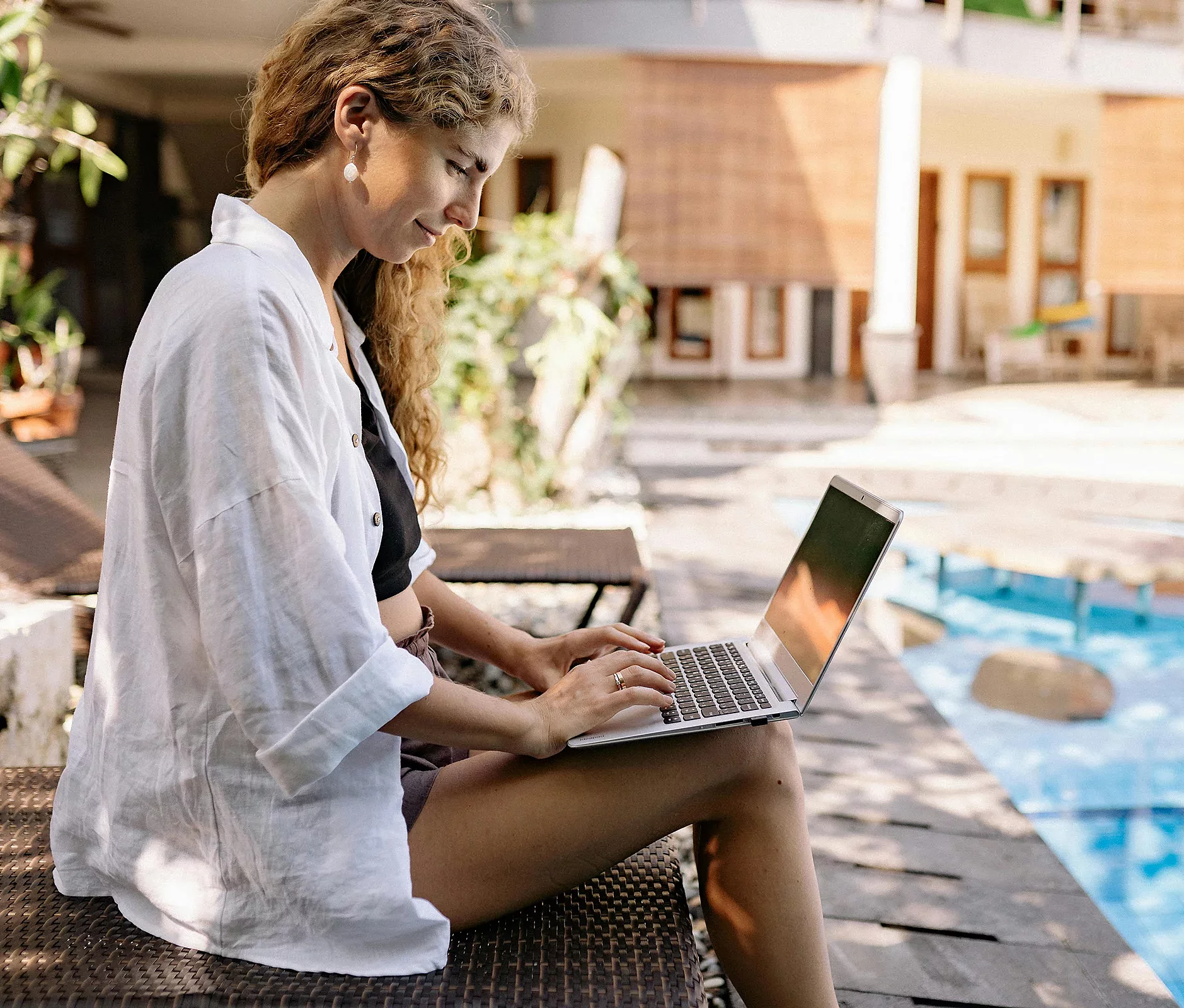 Frau arbeitet am Laptop am Pool