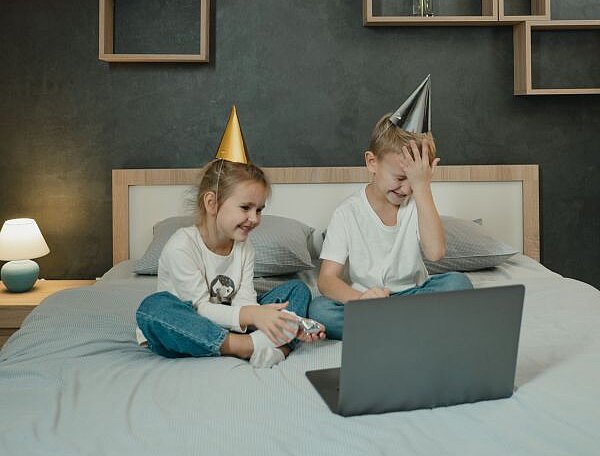 Zwei Kinder sitzen lachend vor einem Laptop