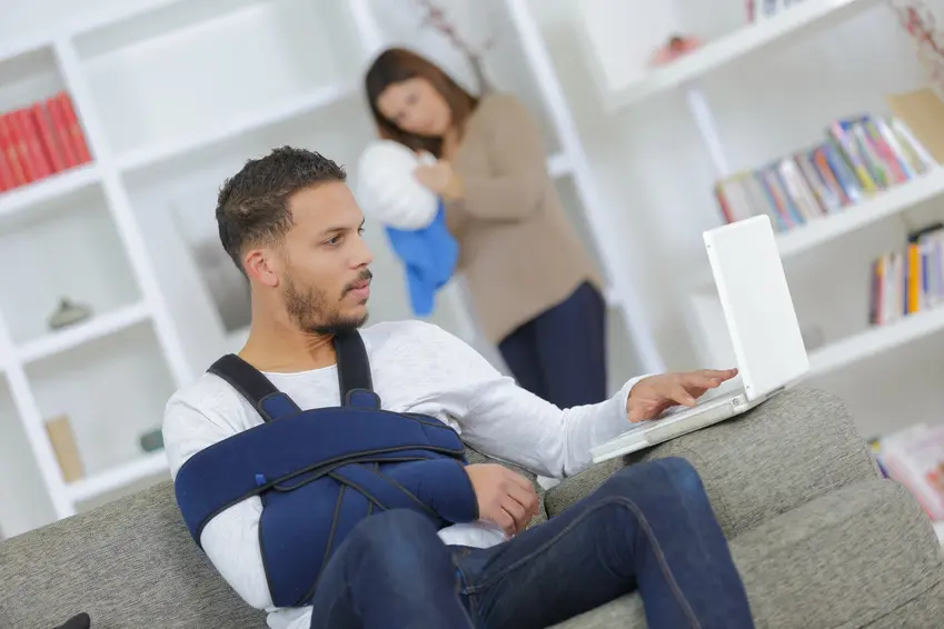 Mann mit Armschlinge sitzt am PC